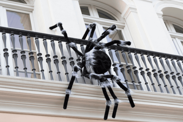 Araignée géante accrochée à la rambarde d'un balcon comme décoration d'Halloween extérieure