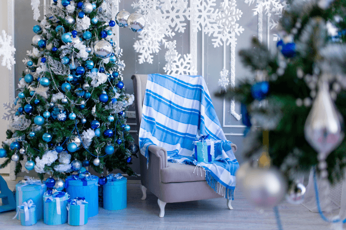 Fauteuil à côté de sapins de Noël décorés en bleu