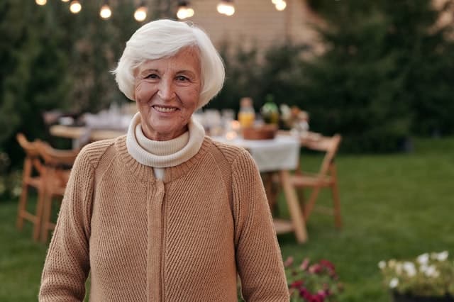 Dame âgée souriant dans la cour de sa maison intergénérationnelle