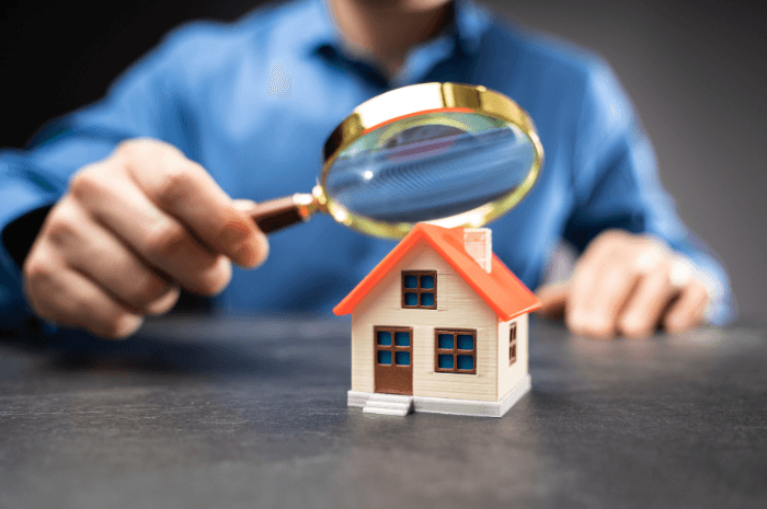 Inspecteur en bâtiment observant une maison avec une loupe