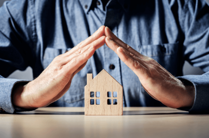 Petite maison en bois protéger par des mains