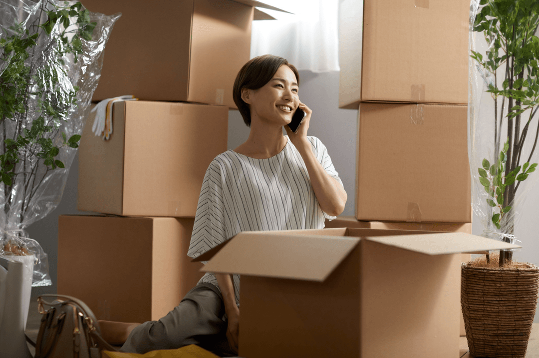 Femme au téléphone parmi des boites de déménagement