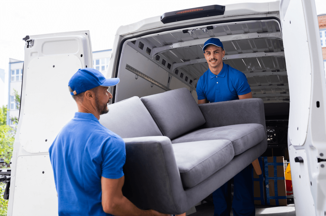 Deux déménageurs qui sortent un sofa gris d'un camion