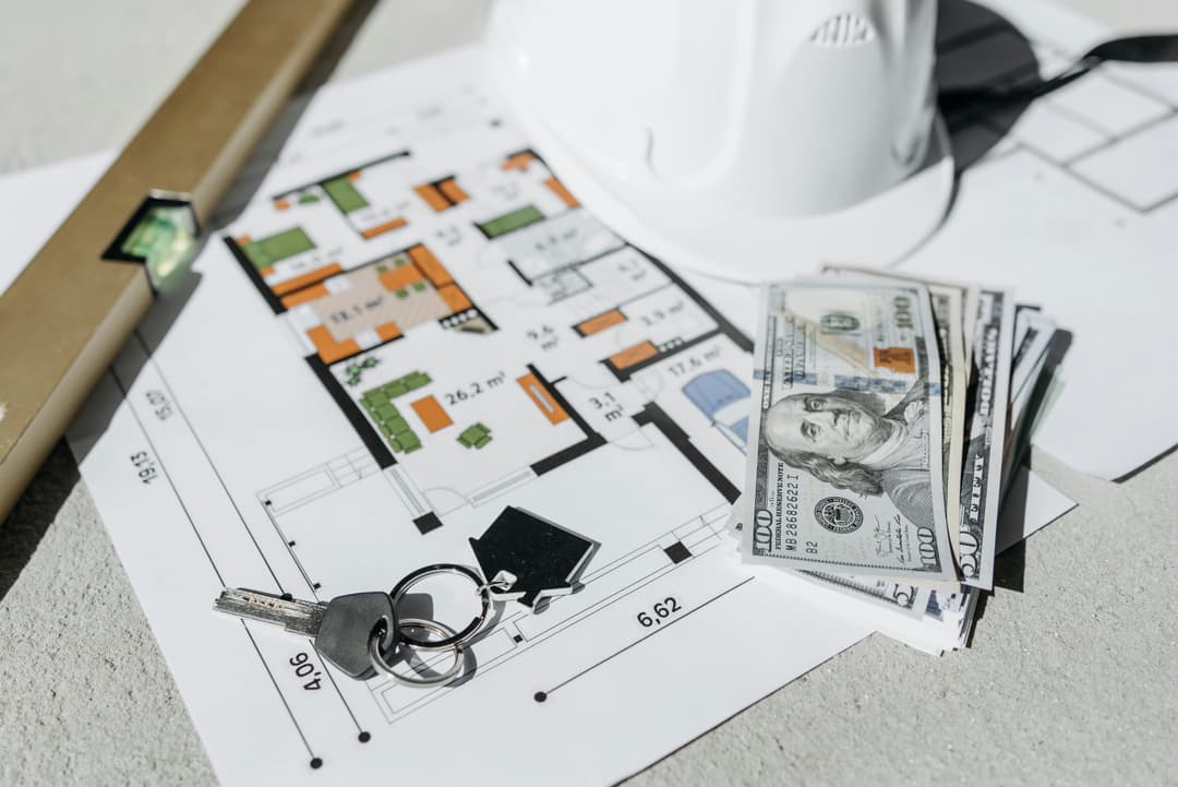 Argent, casque, clé et niveau sur un plan de maison