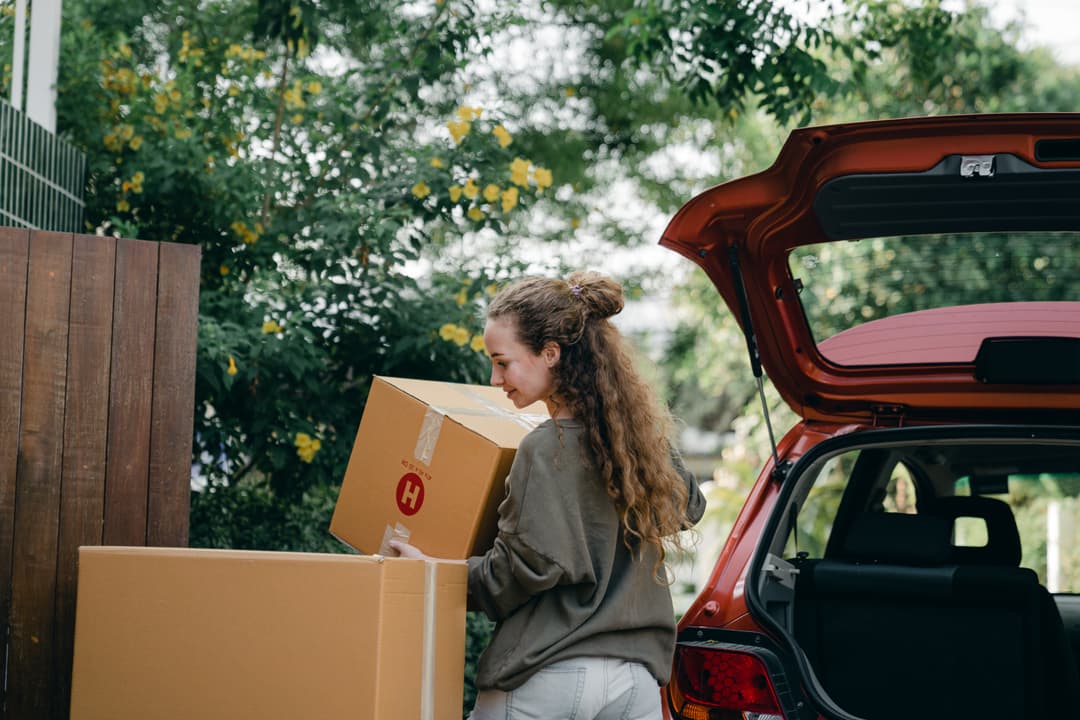 Femme mettant des boites de déménagement dans sa voiture