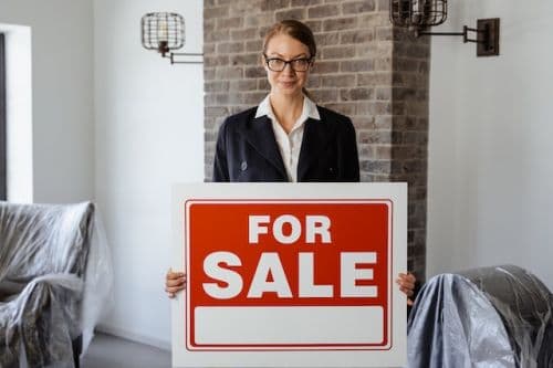 A real estate broker with a for sale sign