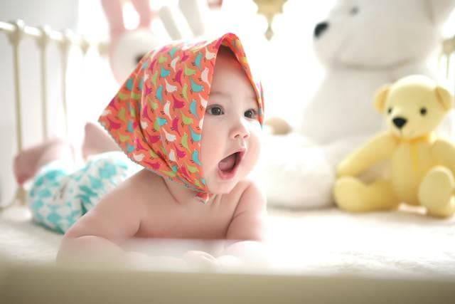 Bébé sur le ventre et entouré de jouet dans un parc pour bébé
