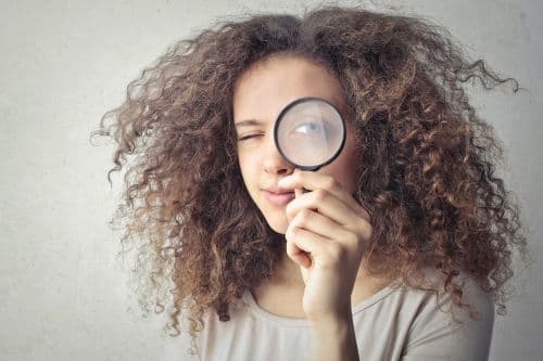 A woman looking in a magnifying glass