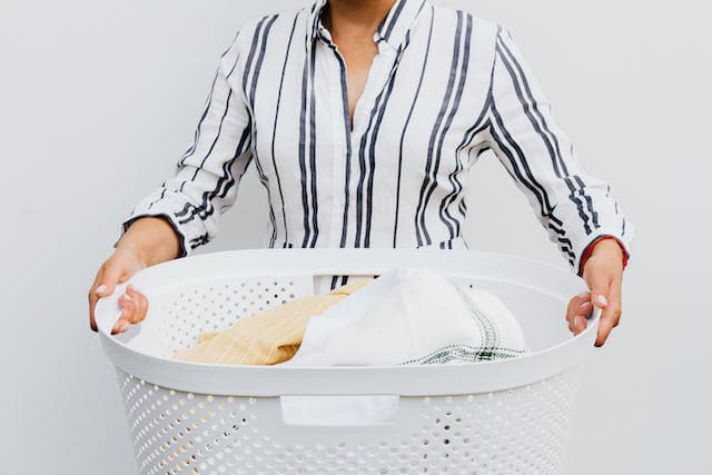 Femme tenant un panier plein de vêtements