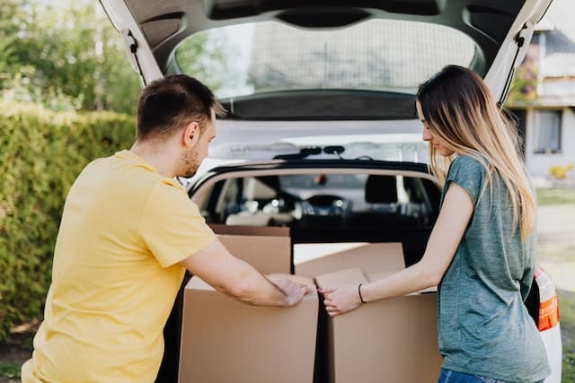 Couple déménageant des boites jusqu’à leur voiture
