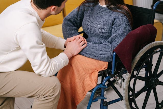Personne en chaise roulante et accompagnateur lui serrant les mains