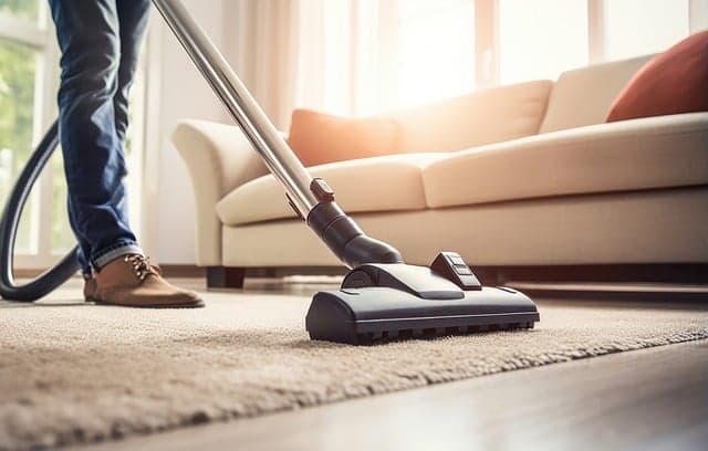 Homme passant l'aspirateur sur un tapis beige à poil court