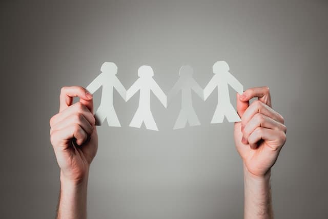 Mains tenant une chaine de personnes en papier représentant l’amitié
