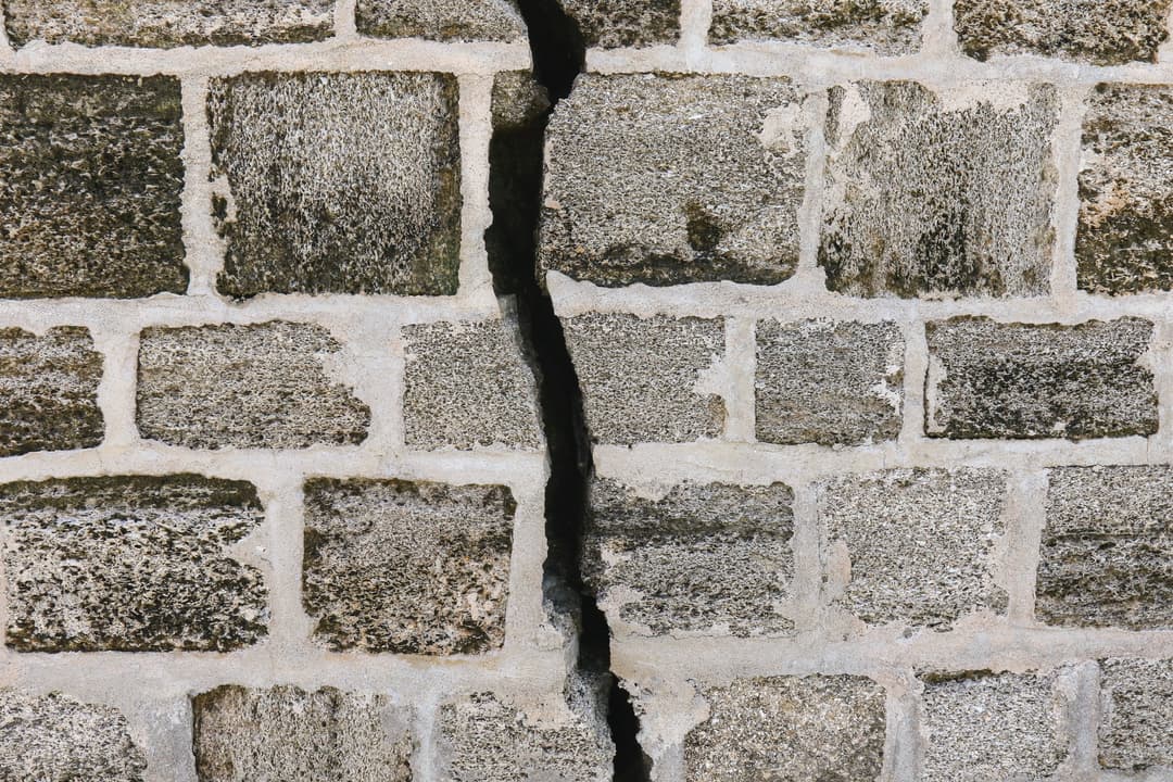 Mur de briques grises fendu vice caché