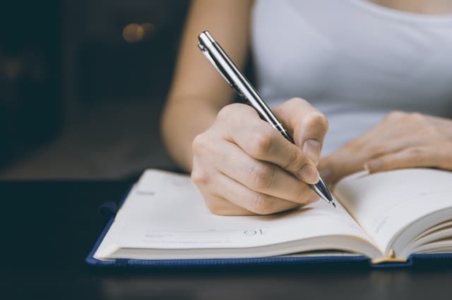 Femme écrivant le texte de son annonce immobilière dans un carnet