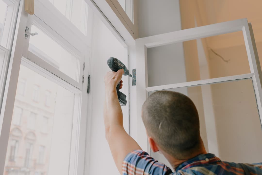 Homme vissant une penture de fenêtre